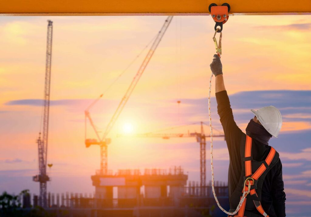 man securing fall protection equipment on construction site