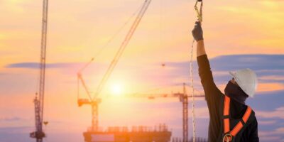 man securing fall protection equipment on construction site