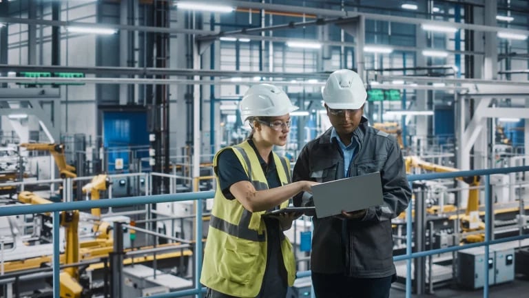 Man in woman in factory setting reviewing asset optimization strategy