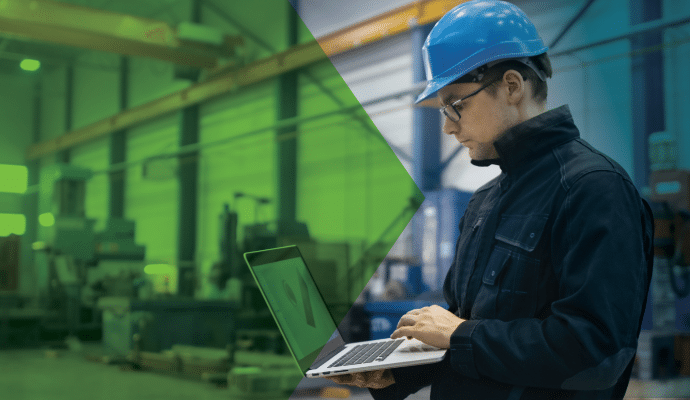 Man working on a laptop ina production environment where the company is working to bridge the IT/OT divide.
