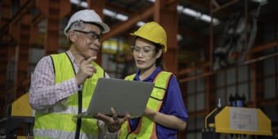 Man and woman in a manufacturing facility reviewing their Installed Base Evaluation report.