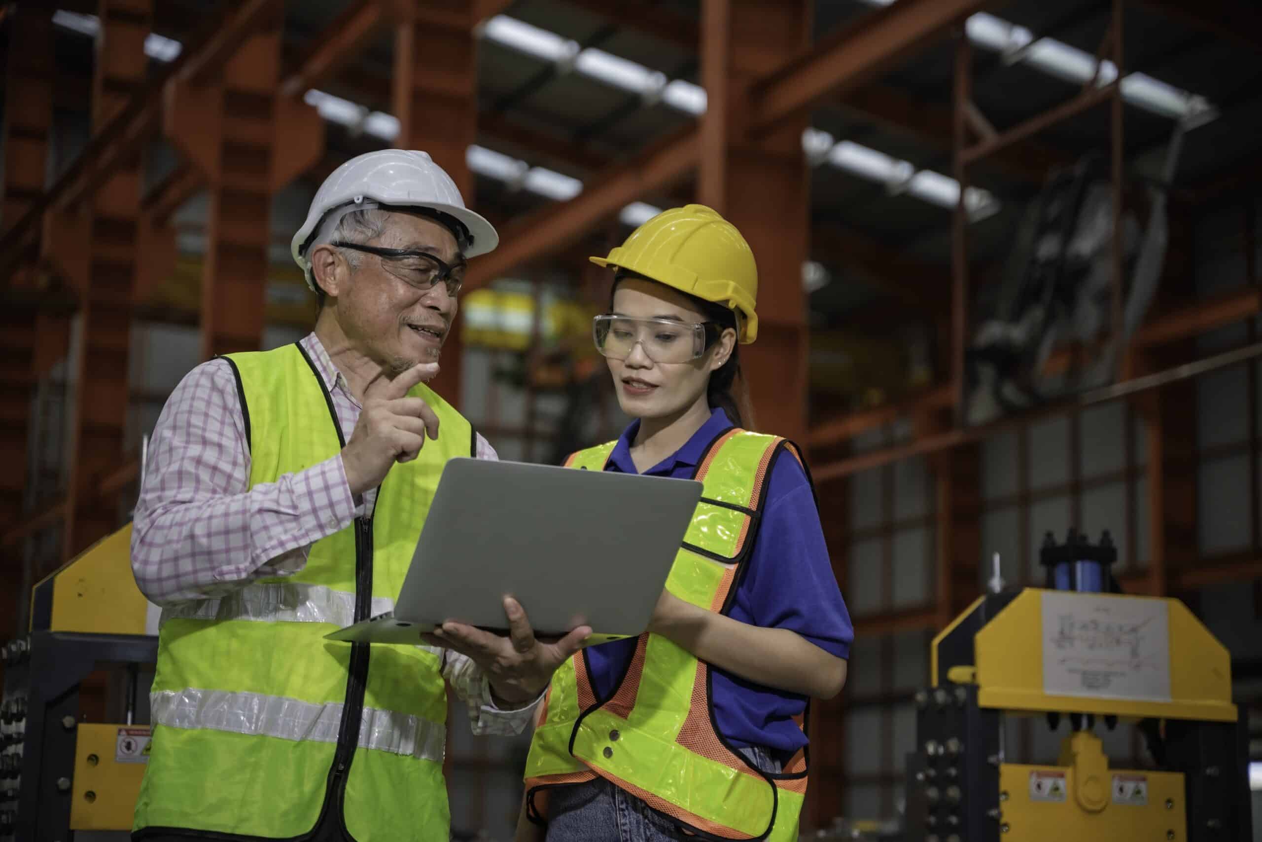 Man and woman in a manufacturing facility reviewing their Installed Base Evaluation report.