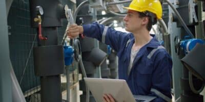 Factory maintenance technician performing predictive maintenance services on equipment.