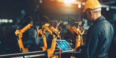 Industrial engineer manipulating robots workers enabled by a strong industrial wireless network.